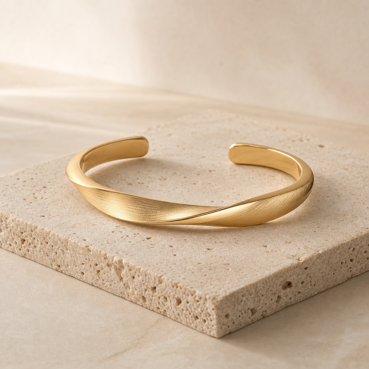 Sculptural brushed gold cuff bracelet on pale stone