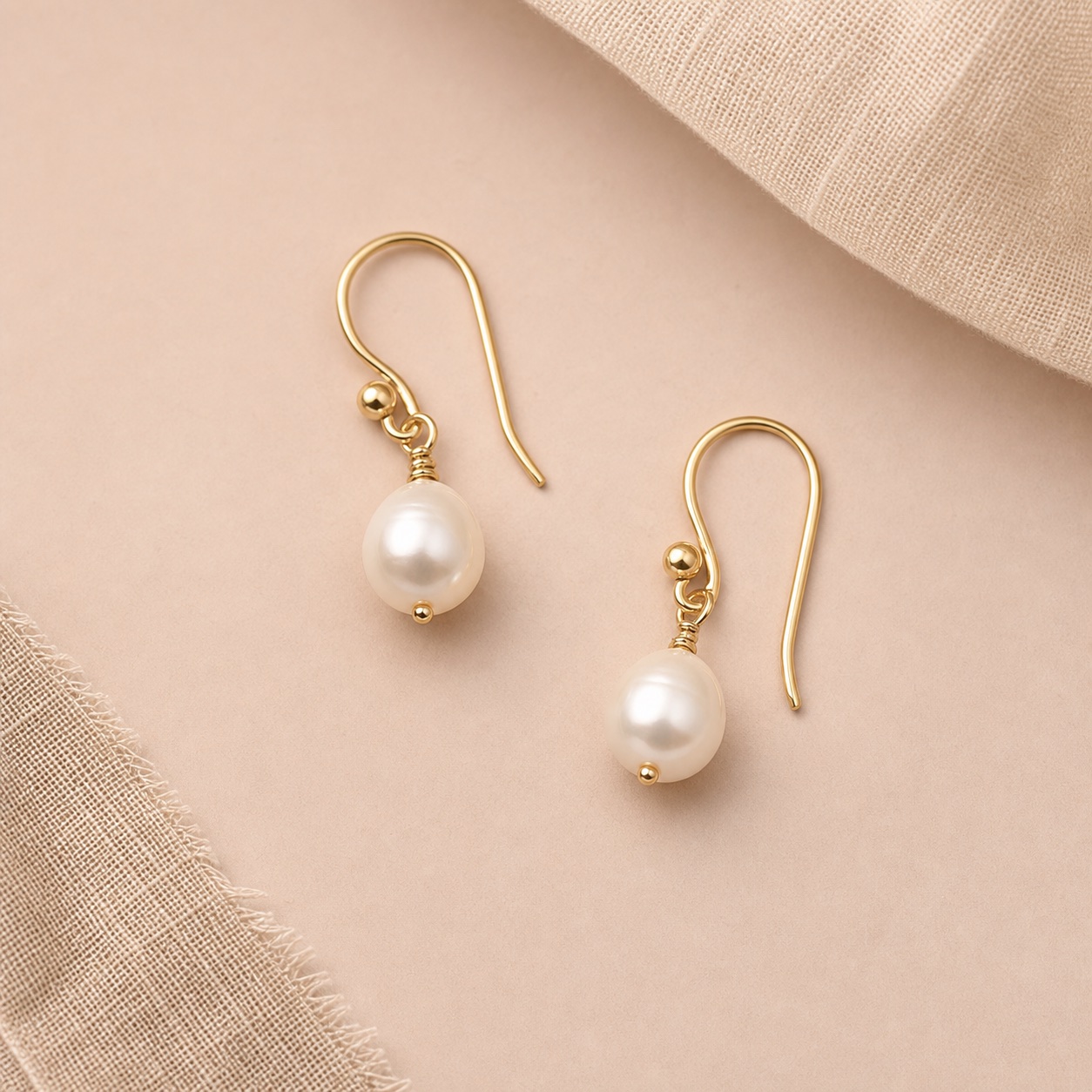Pearl drop earrings in gold on blush fabric